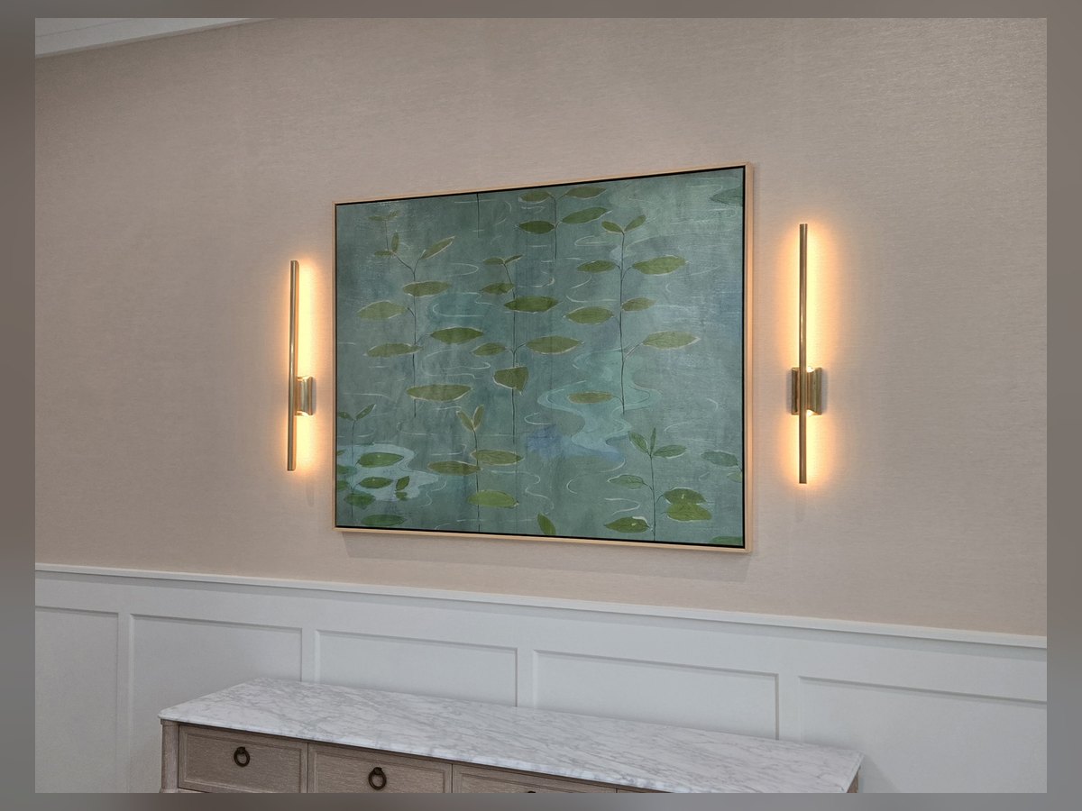 Framed art hung between two wall sconces