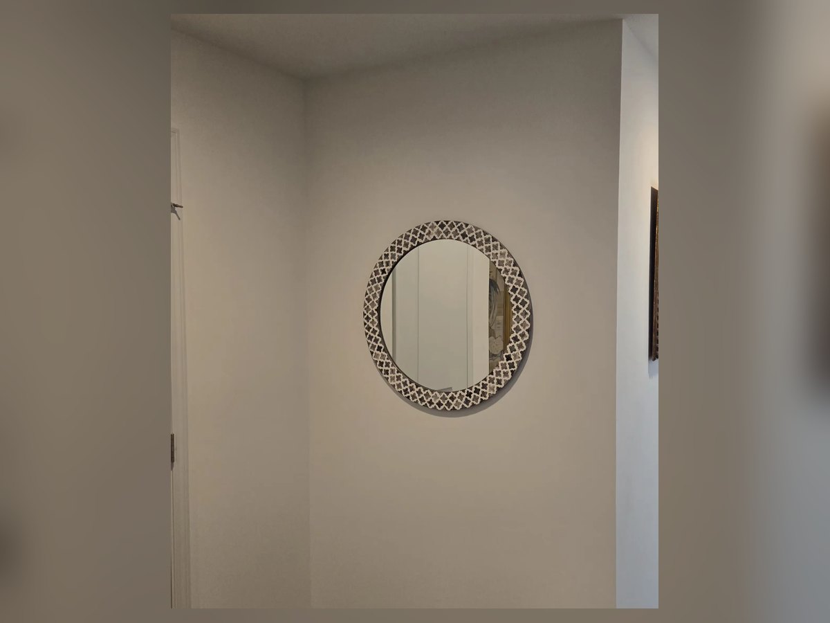 Round mosaic-frame mirror hung in a hallway