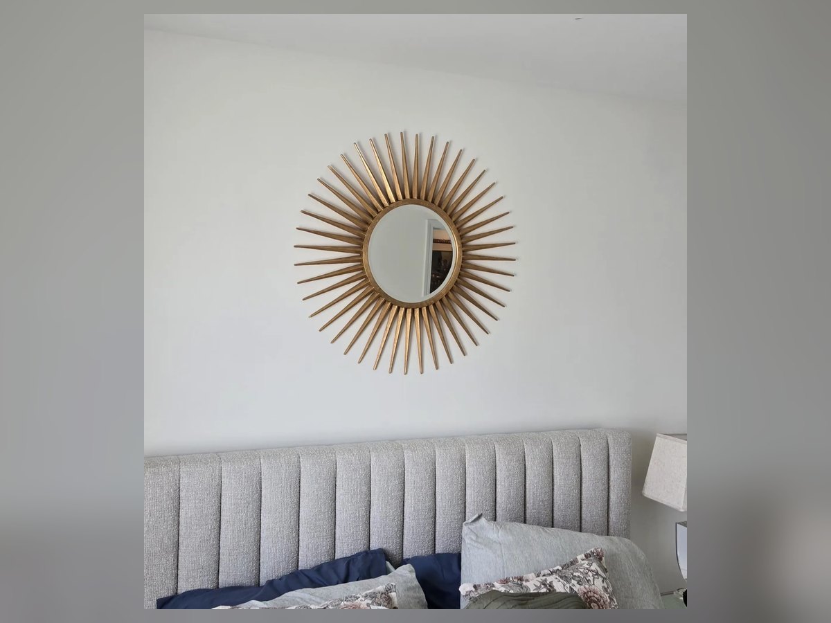 Gold sunburst mirror hung above a bed